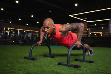Fototapeta na wymiar Strong muscular African sportsman doing pushups at the gym, copy space. Athletic handsome man with toned powerful body exercising, doing push-ups
