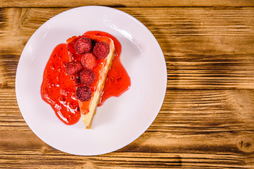 White plate with cheesecake New York and raspberries on wooden table. Top view