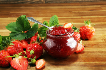 strawberry jam with fresh strawberries and mint. marmalade on spoon and jar on brown wood
