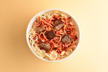 Paper cup with instant ramen noodles with beef and vegetables.