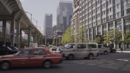 Vehicles passing under train bridge near Tokyo Station, Japan - Sunny day - Wide steadicam shot