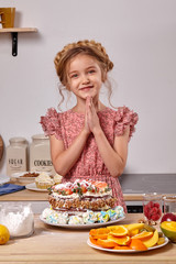 Little girl is making a homemade cake with an easy recipe at kitchen against a white wall with shelves on it.