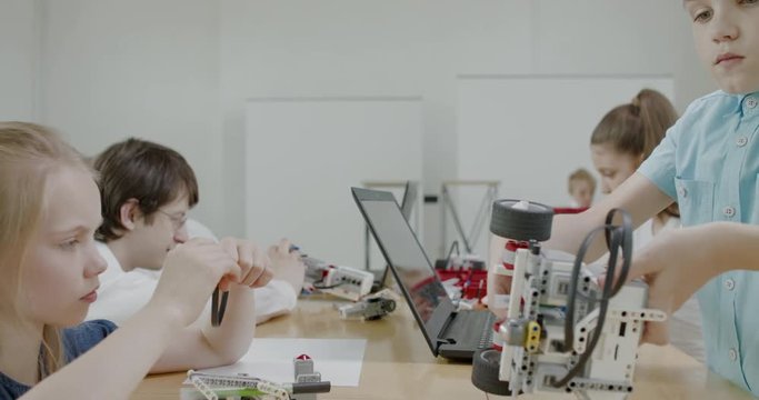 Curious kids working on a functional programable robot during robotics class at school. 4K UHD 60 FPS SLOW MOTION