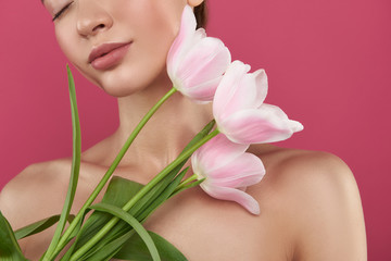 Beautiful young woman with full rosy lips holding tulips