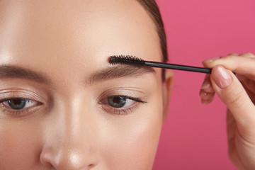 Female beautician hand shaping lady eyebrows with brush