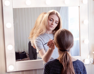 Makeup artist makes evening make-up of young girl brown-haired. Concept of beauty, skin care, make-up.