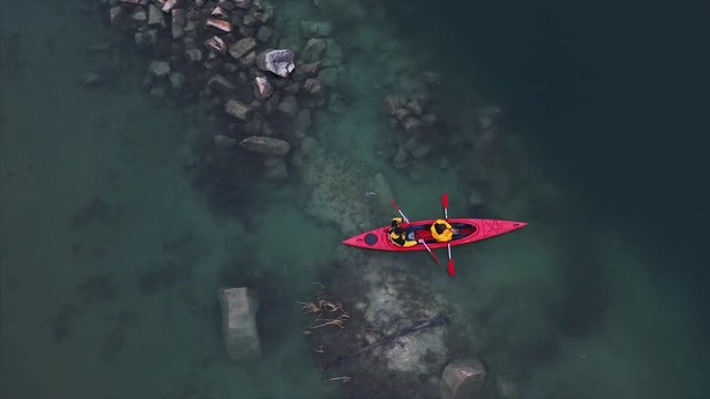 two athletic man floats on a red boat in river