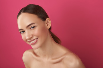 Joyful girl with perfect skin posing against pink background