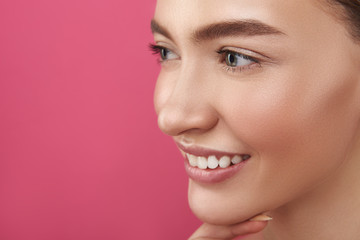 Joyful lady with perfect skin standing against pink background