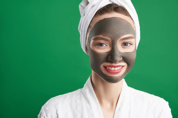 Charming young woman using clay facial mask after shower