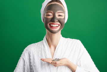 Cheerful girl with towel on her head holding cosmetic clay