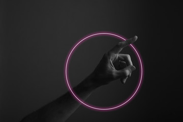 Hand pointing a finger against a dark background with abstract neon light glow
