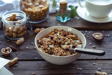 Healthy lifestyle breakfast bowl plate with granola and spoon on brown wooden table background, cereal granola food with nuts seed organic muesli morning diet oat meal for health care concept
