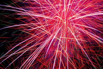 Flickering lights are a bright salute of abstract red yellow blue cyan luminescent traces of petals on long exposure on a night black sky background. Fireworks on the day of the city of Ufa, Russia.