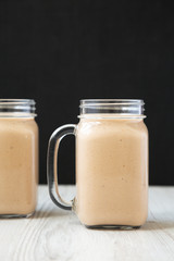 Healthy banana apple smoothie in glass jars, side view. Close-up.