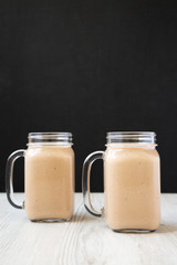 Healthy banana apple smoothie in glass jars, side view. Close-up.