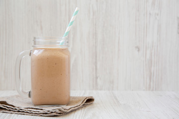 Banana apple smoothie in a glass jar mug, side view. Copy space.