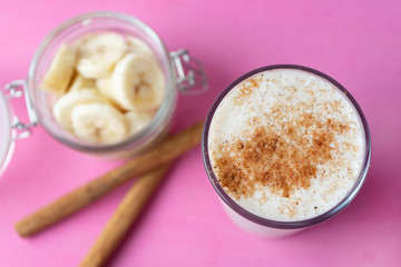 Banana smothie or milkshake with cinnamon on pink  background