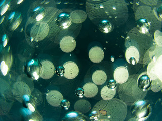 Abstract macro of air bubbles embedded in glass with green accents.