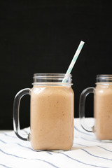 Healthy banana apple smoothie in glass jars, side view. Close-up.