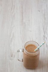 Healthy banana apple smoothie in a glass jar over white wooden surface, low angle view. Copy space.