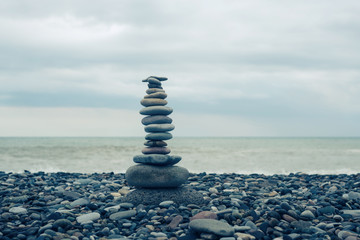 Fototapeta na wymiar relaxation at sea. Stack of stones on beach - nature background. Stone cairn on blurry background, pebbles and stones