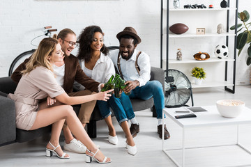 cheerful multicultural men toasting with attractive women in living room