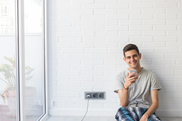 young man with mobile phone at home in the morning