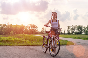 Active life. A young woman with cycling at the sunset in the park. Bicycle and ecology lifestyle concept.