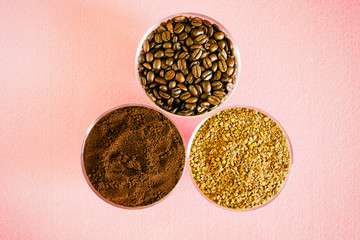 Variety of coffee - three types in one picture: roasted beans, soluble granulated and ground. In round glass bowls on a pink background. Vintage processing
