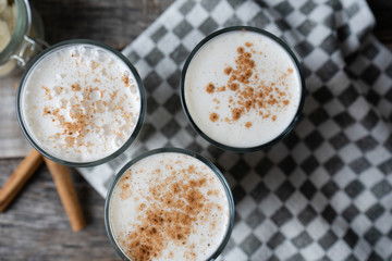 Banana smothie or milkshake with cinnamon on wood background
