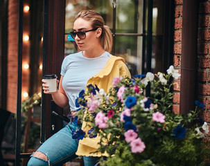 Young attractive woman with takeaway cup of coffee is enjoying summer outside.