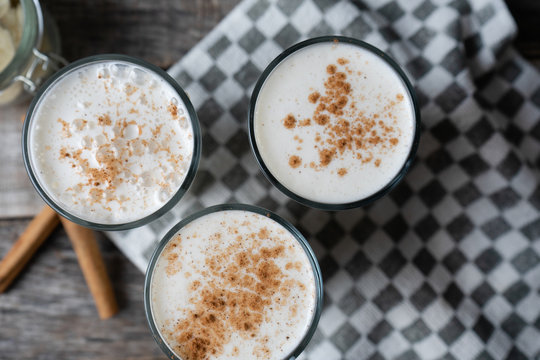 Banana smothie or milkshake with cinnamon on wood background