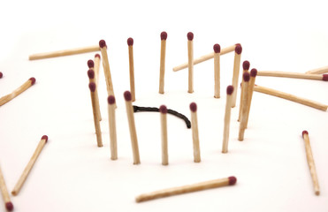 matches stand in the circle around a burnt match on a white background
