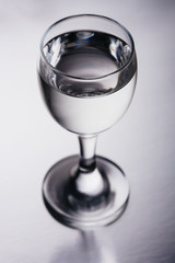 Wineglass with transparent drink on silver background isolated