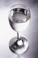 Wineglass with transparent drink on silver background isolated