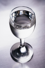 Wineglass with transparent drink on silver background isolated