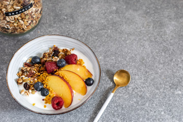 Granola with yogurt fresh peach, blueberry, raspberry on the table - healthy breakfast