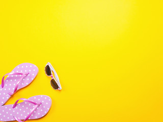 Summer flat lay. Beach accessories pink flip flops and sunglasses on yellow background. Summer trevel and vacation concept