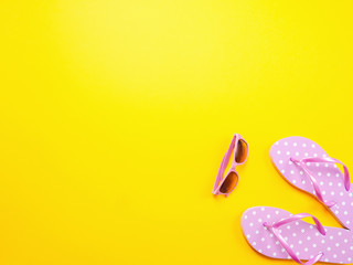 Summer flat lay. Beach accessories pink flip flops and sunglasses on yellow background. Summer trevel and vacation concept