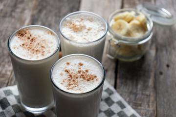 Banana smothie or milkshake with cinnamon on wood background