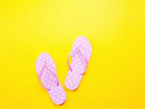 Top view image of pink flip flops on yellow background. Summer trevel and vacation concept