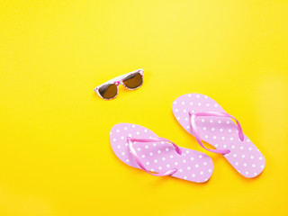 Summer flat lay. Beach accessories pink flip flops and sunglasses on yellow background. Summer trevel and vacation concept