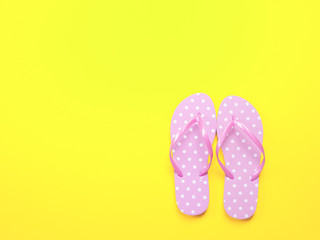 Top view image of pink flip flops on yellow background. Summer trevel and vacation concept