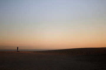 Fototapeta na wymiar Alone man on the beach with silhouette of a dune