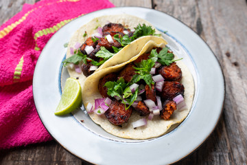 Mexican food: Delicious red chorizo tacos on wooden background