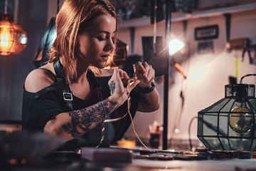 Busy diligent woman is working at lamp studio with tape and colourful triangles.