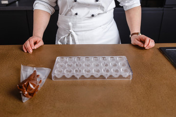 Close-up professional man chef holding hands on stone table in bakery. Chef is ready to prepare chocolate. Clean and tidy table for cooking. chef making chocolate decoration chocolate face in kitchen