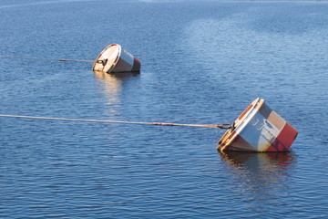 Red-white buoys are in the water. They stretch the ropes beyond the frame.