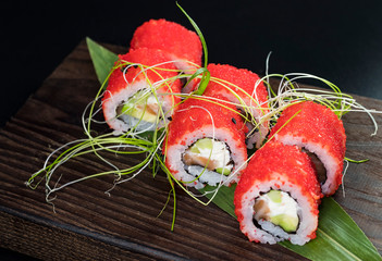 Japanese traditional rolls with seafood and fish, vegetables, on a black background.